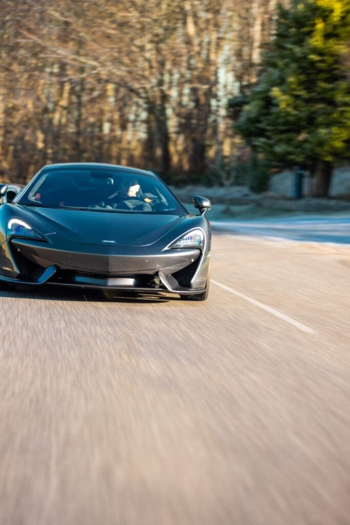 Sort sportsvogn kører på solrig vej