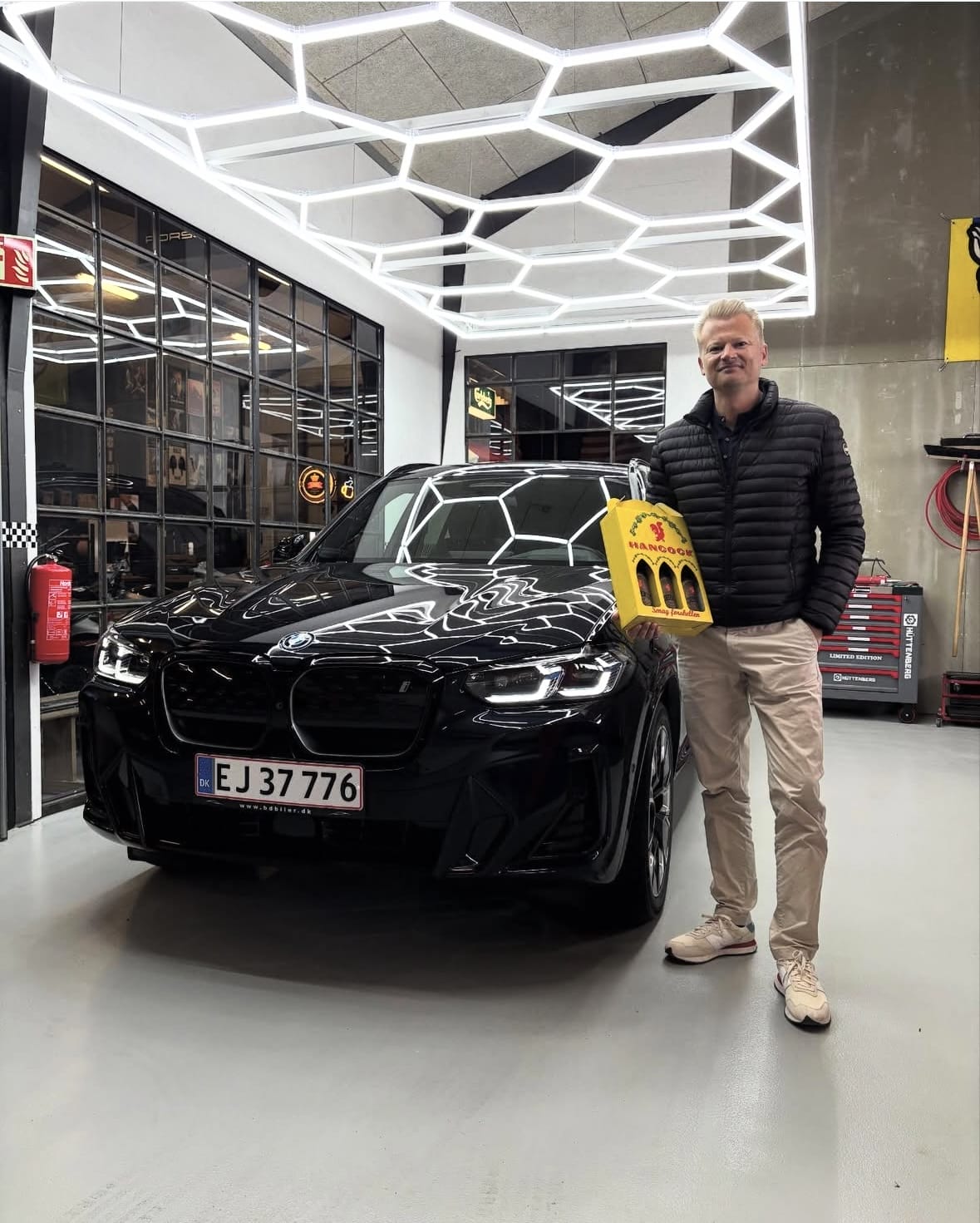 Mand står ved sort BMW i garage