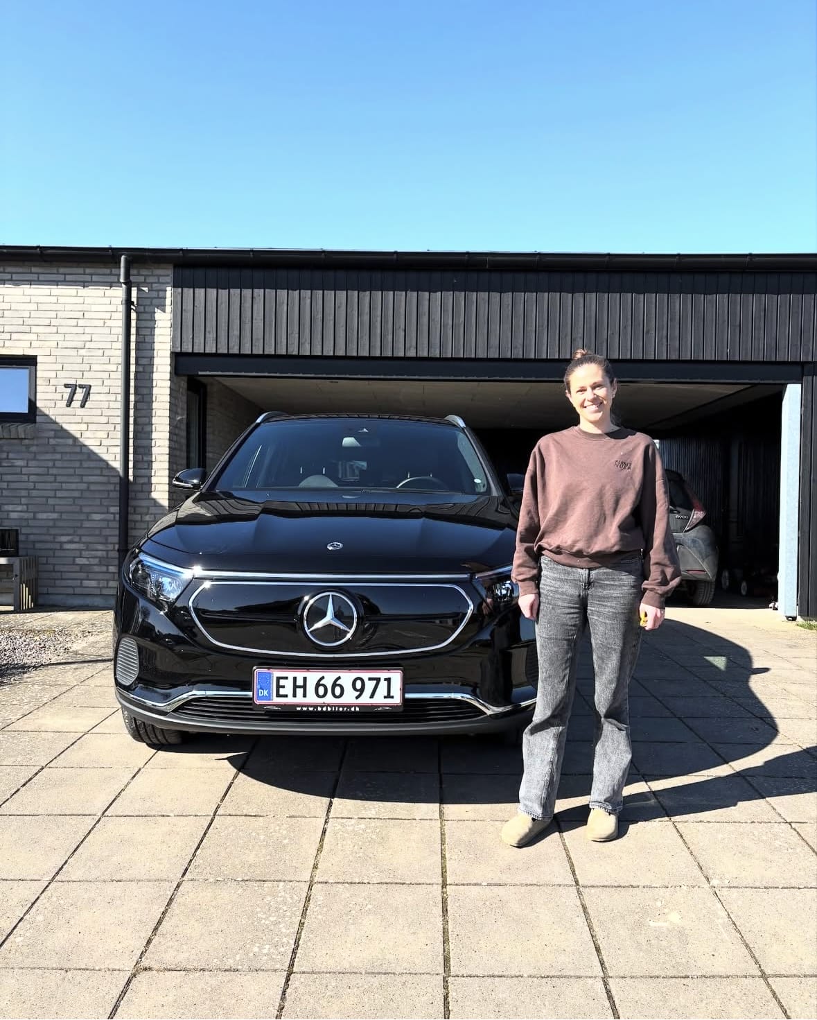 Person står foran sort Mercedes-bil ved hus