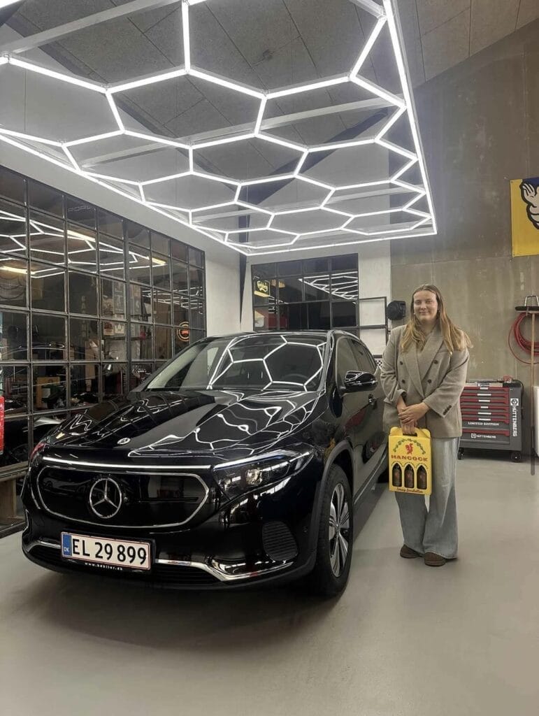 Kvinde står ved sort Mercedes i garage