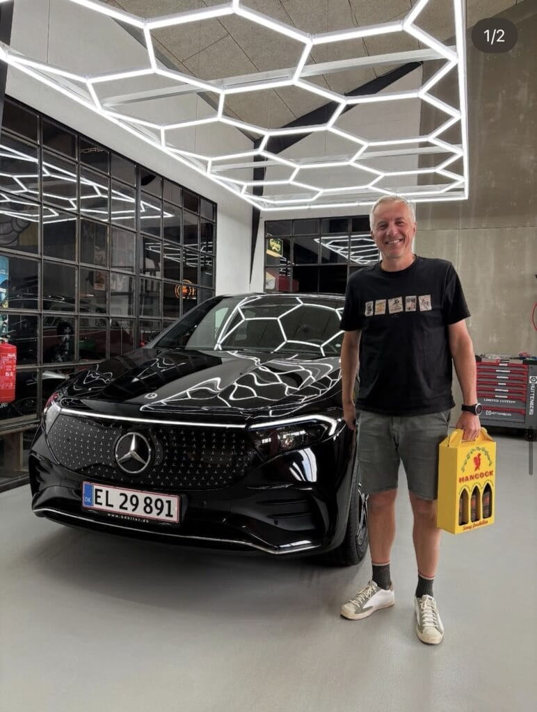 Mand står ved sort Mercedes i garage
